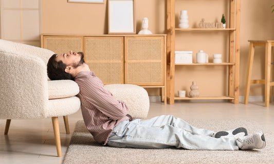 Person resting beside a sofa while experiencing low energy